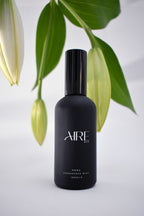Bloom Aire & Co home fragrance mist bottle with green leaves in the background