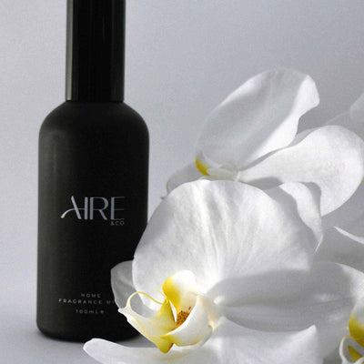 Aire & Co home fragrance mist with white flowers on a light gray background