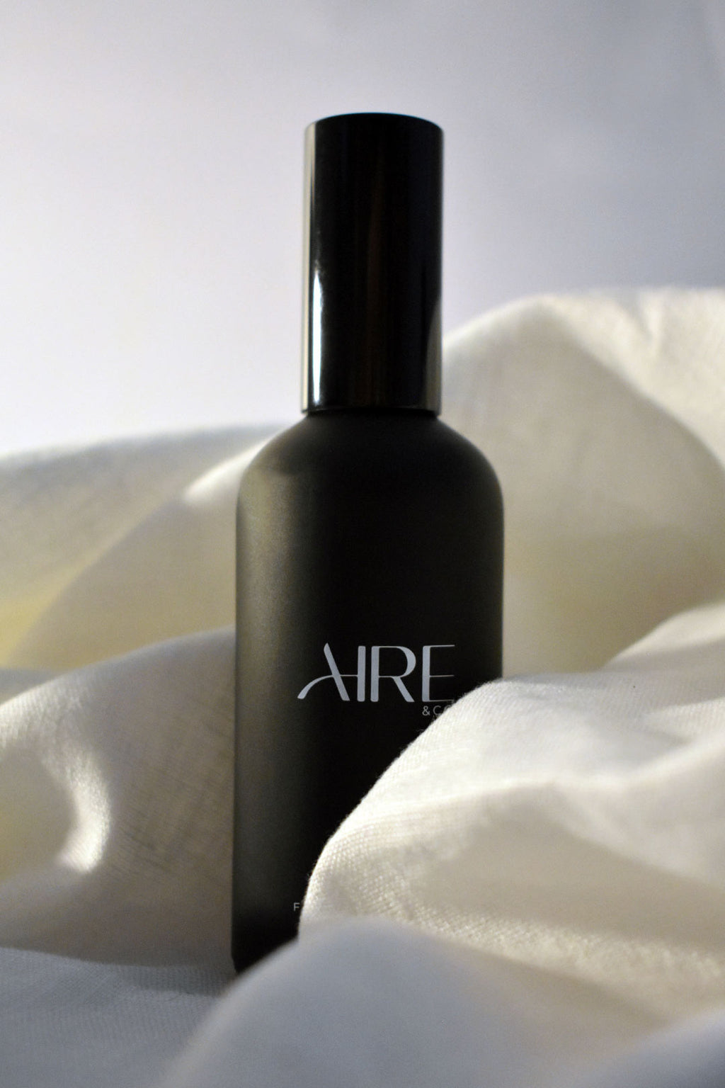 Linen Aire & Co home fragrance mist bottle surrounded by white fabric