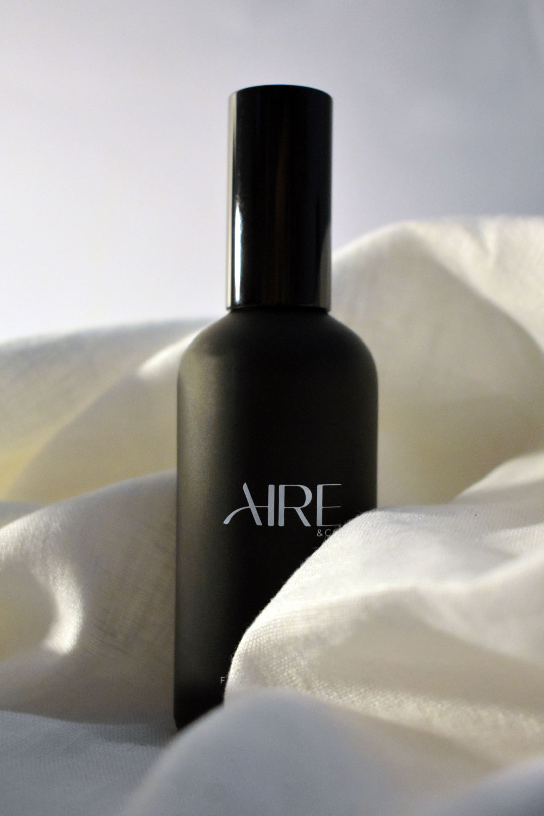Linen Aire & Co home fragrance mist bottle surrounded by white fabric
