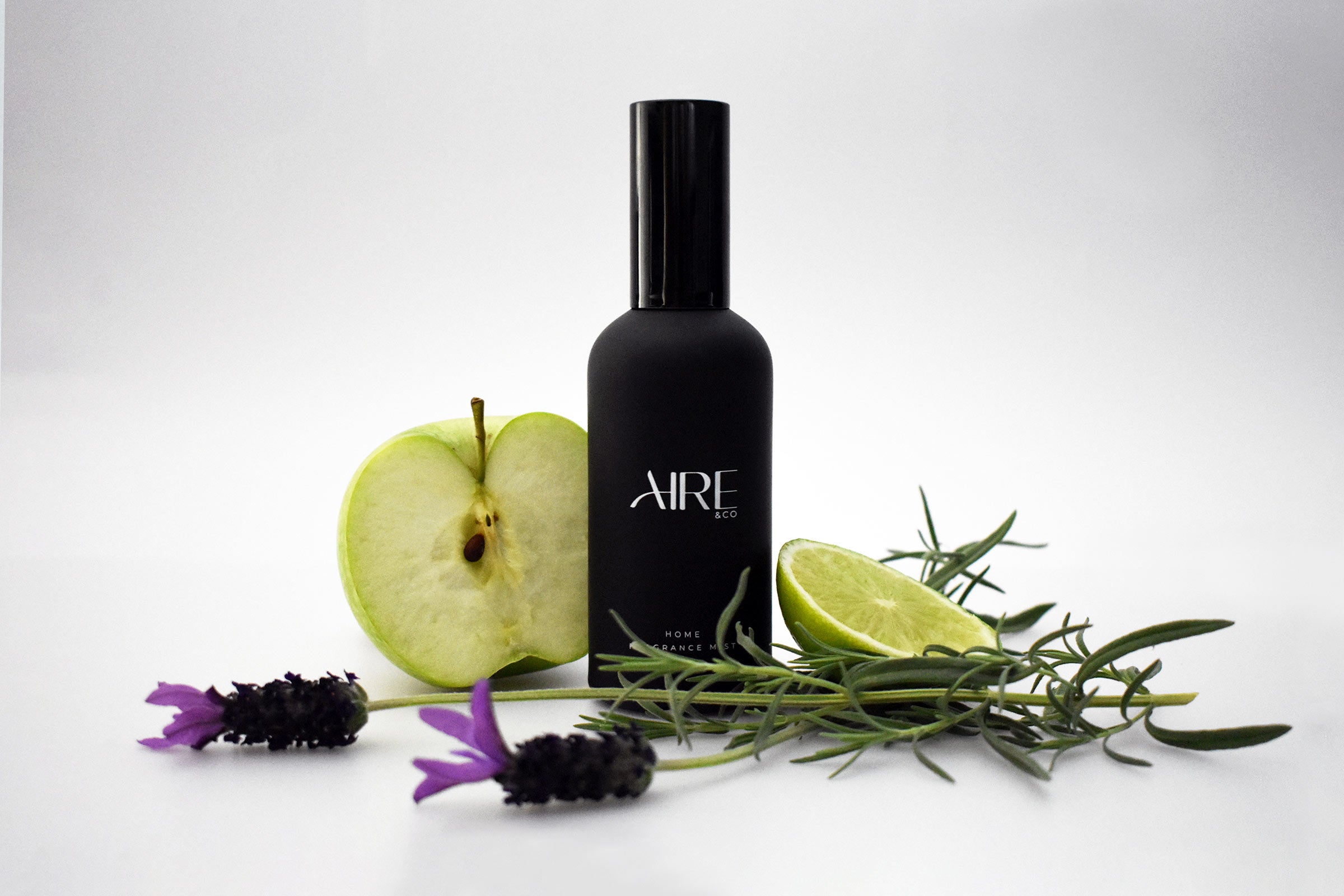 Linen Aire & Co home fragrance mist bottle with a green apple, lime, and lavender stems on a white background.