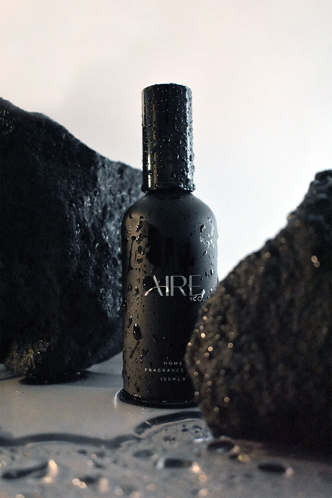 Ocean home fragrance mist bottle by Aire & Co on coastal rocks with water