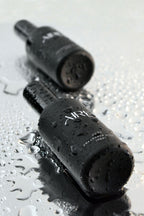 Two black ocean Aire & Co home fragrance mist bottles on a wet surface