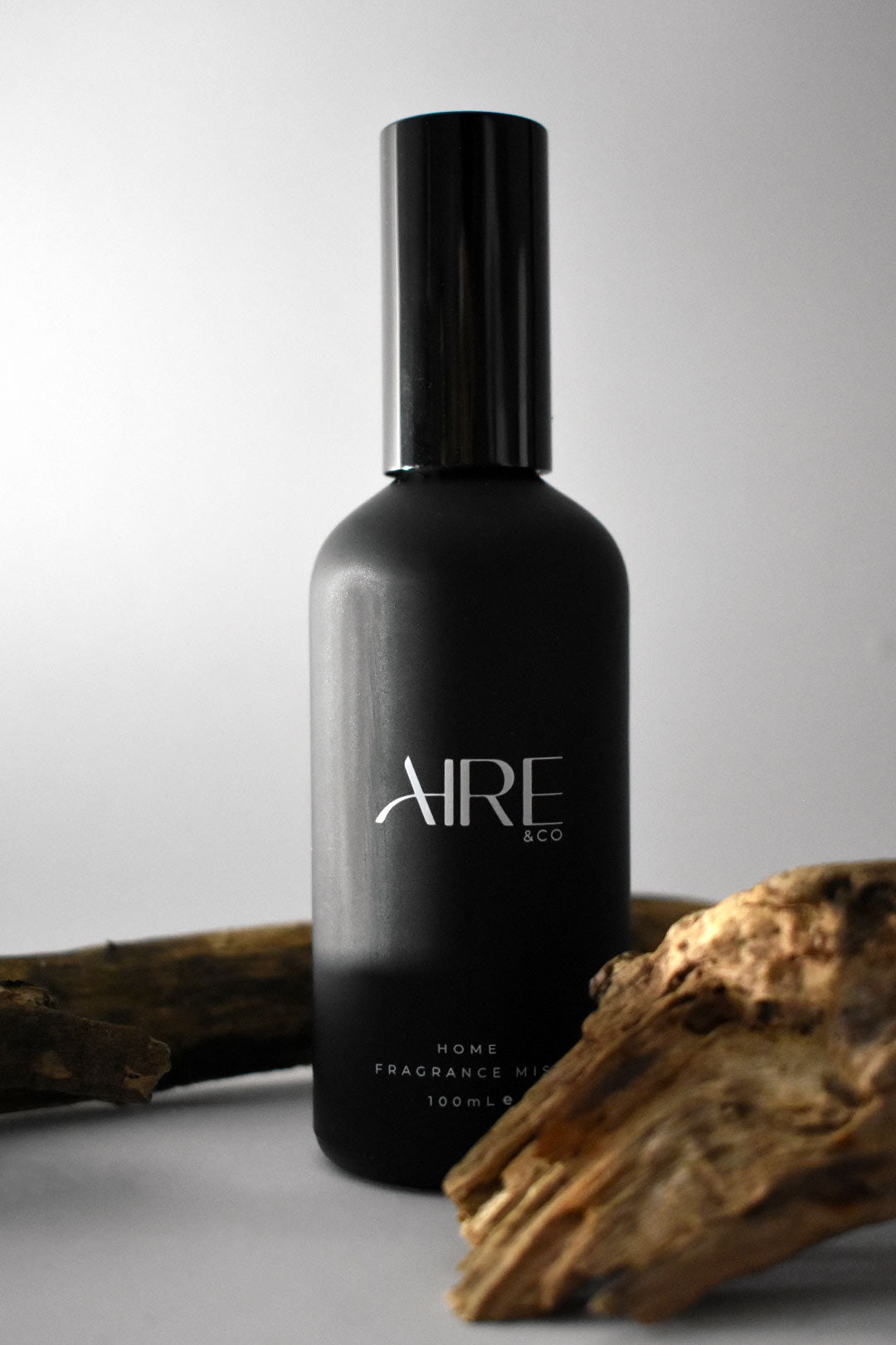 Stone home fragrance mist bottle by Aire & Co with wooden elements on a gray background