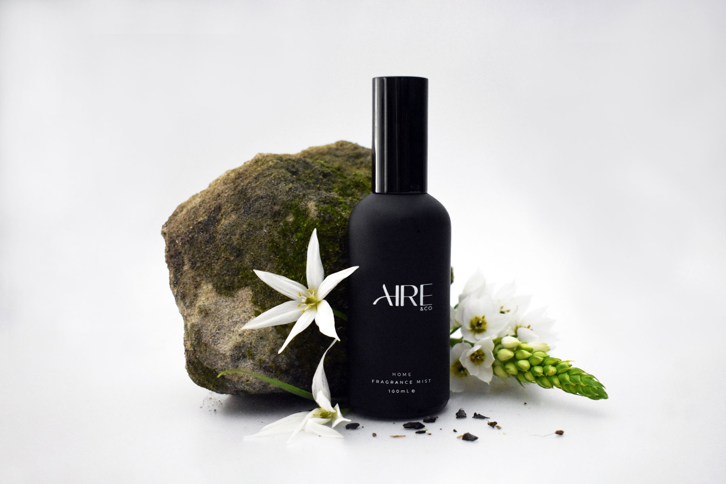 Stone Aire & Co home Fragrance mist bottle with flowers and a rock on a white background