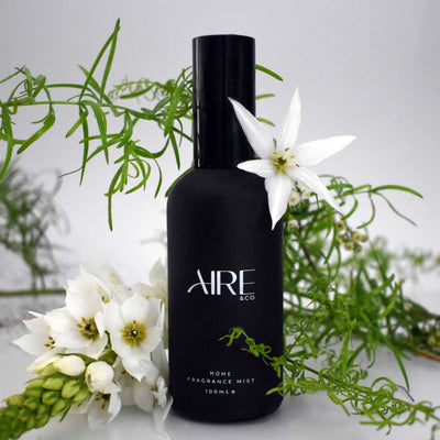 Aire & Co  home fragrance mist bottle with white flowers and greenery on a light background